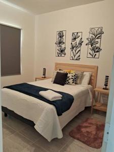 Departamento Ciudad MayaKoba 2 habitaciones في بلايا ديل كارمن: غرفة نوم بسرير كبير عليها ثلاث لوحات