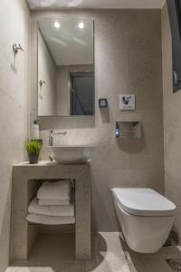 a bathroom with a sink and a toilet and a mirror at Aethir Urban Stay by Raise in Athens