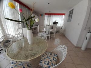 une salle à manger avec une table en verre et un vase avec des fleurs dans l'établissement Departamento agradable con la mejor vista al cerro, à Tehuacán