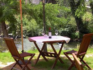 a table with a bottle of wine and two chairs at Hotel Rural Casa de Campo in Soto de Cangas