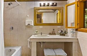 a bathroom with a sink and a mirror and a tub at Sachatamia Lodge in Mindo
