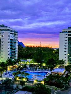 vista para uma piscina numa cidade à noite em Apartamento por temporada RJ próximo ao Riocentro, Parque Olímpico e Jeunesse Arena no Rio de Janeiro