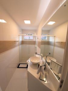 uma casa de banho branca com um lavatório e um espelho em Apto novo no centro em Pomerode