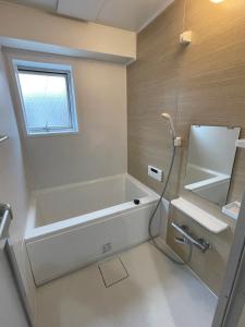 a bathroom with a tub and a sink and a window at ROYAL YONEGAHAMA ｌ米が浜通 in Kusugaurachō
