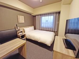 a hotel room with a bed and a window at Hotel Route-Inn Yamanashi Chuo in Chuo