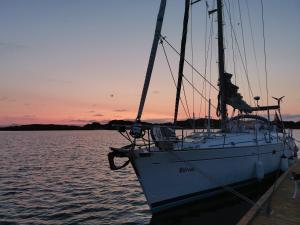 Liveaboard sailing tour in Harstad islands في هارستاد: قارب شراعي مرسى على رصيف مع غروب الشمس