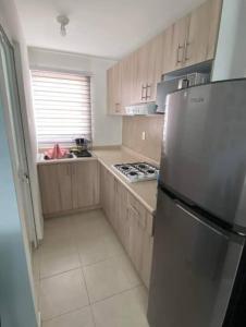 a kitchen with wooden cabinets and a stainless steel refrigerator at Departamento-Poliforum Feria Estadio Zona Piel. in León