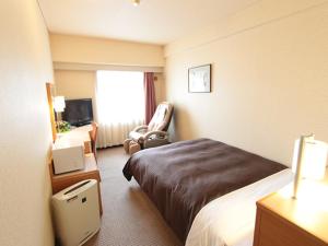 Habitación de hotel con cama y silla en HOTEL LiVEMAX BUDGET Yokohama Kannai en Yokohama