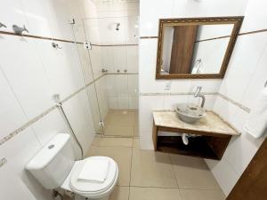 a bathroom with a toilet and a sink and a mirror at Refúgio da Lagoinha - Centro de Bombinhas in Bombinhas