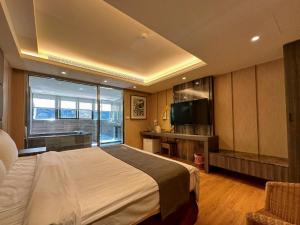 a bedroom with a large bed and a television at Ming Zhi Hot Spring Hotel Building B Dongguan Hot Spring Hotel in Heping