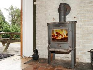 a wood stove in a room next to a brick wall at Holiday home Melby IX in Melby