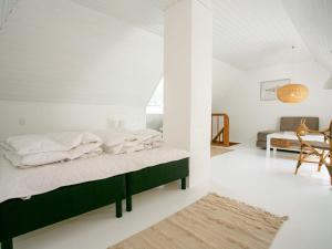 a bedroom with a green bed in a white room at Holiday home Rudkøbing XX in Rudkøbing