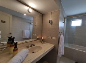 a bathroom with a sink and a mirror and a tub at Inti Llaqta Hotel & Suites in Lima