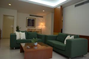 جناح ذا مابل في كوالالمبور: غرفة معيشة بها كنبتين خضراء وطاولة
