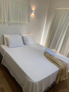 uma cama grande com lençóis brancos e almofadas em Luz da Lua Beach House São Miguel do Gostoso em São Miguel do Gostoso
