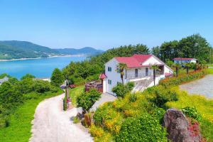 a house on a hill next to the water at Travel Sketch Pension in Geoje 