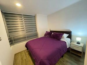 a bedroom with a purple bed and a window at Departamento con piscina. in Viña del Mar