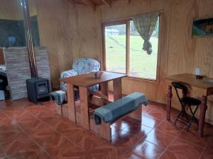 a dining room with a table and chairs and a window at Cabaña Kiñeco y tinaja in Melipeuco