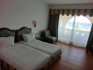 a bedroom with two beds and a chair and a window at Domina coral bay Sultan - private room in Sharm El Sheikh