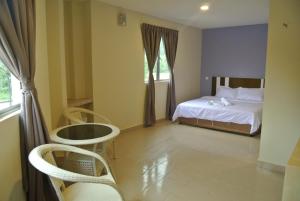 a bedroom with a bed and chairs and a window at Five Hotel in Seremban