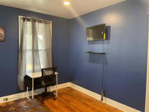 Cette chambre est dotée d'un mur bleu avec une chaise et un bureau. dans l'établissement fashionably cozy place, à Meriden