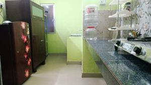a kitchen with a black counter and a refrigerator at The Leisure Home Stay in Shādipur +17 photos