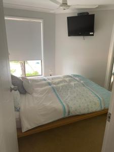 a bedroom with a bed with a television on the wall at Mermaid Waters 3 Bedroom Home Free Wifi - Close to the beach - shops in Gold Coast