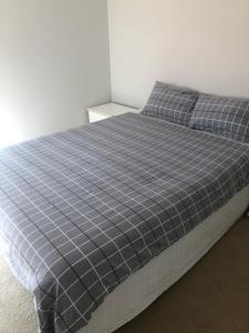 a bed with a blue and white checkered blanket at Mermaid Waters 3 Bedroom Home Free Wifi - Close to the beach - shops in Gold Coast