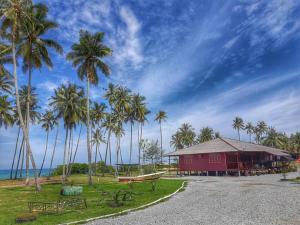 a red building with palm trees in front of the ocean at MILLBROOK HOUSE TERENGGANU in Kampong Pasir Puteh