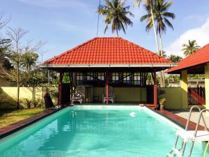 a swimming pool in front of a house with a red roof at MILLBROOK HOUSE TERENGGANU in Kampong Pasir Puteh