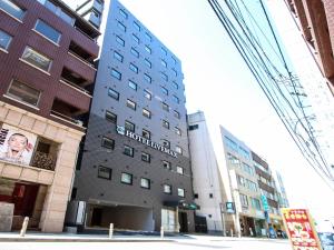 a tall building with a sign on the side of it at HOTEL LiVEMAX Yokohama Kannai Ekimae in Yokohama