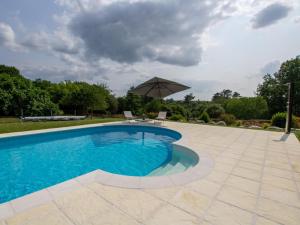 a swimming pool with an umbrella and a patio at Maison Authentique avec Piscine, Étang Privatif et Confort Moderne en Dordogne - FR-1-616-332 in Agonac