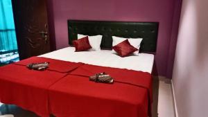 um quarto com uma cama vermelha e branca com lençóis vermelhos em The Leisure Home Stay em Shādipur