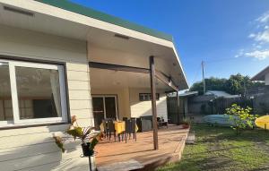 a house with a wooden deck with chairs on it at Kai Palmer Lodge in Punaauia