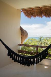 a hammock in a room with a view of the ocean at Puerta del Cielo Hotel Origen in Bacalar