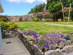 a garden with purple flowers and a stone wall at Villa Pio Luxury Apartment 3km from historic Cong, Ashford Castle, Ashford Lodge in Cong