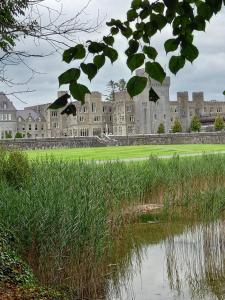 a large castle with a pond in front of it at Villa Pio Luxury Apartment 3km from historic Cong, Ashford Castle, Ashford Lodge in Cong