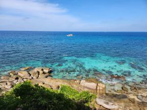 a boat in the water next to a rocky shore at Tao Thong Villa 2 in Ko Tao