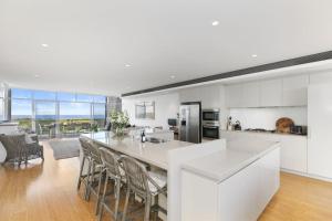 a kitchen with a large island with chairs in it at Beachfront Haven at Magenta in Magenta