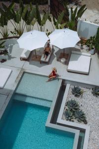 a woman sitting in a chair next to a pool with umbrellas at Sky House Santa Teresa - Adults only in Santa Teresa Beach