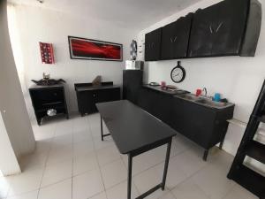 uma cozinha com armários pretos e piso em azulejo branco em departamento rosa em Tehuacán