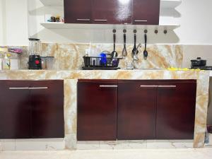 a kitchen counter with brown cabinets and utensils at hostal la niña carmen in Cartagena de Indias