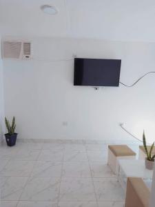 Habitación blanca con TV de pantalla plana en la pared en casa pileta patio indio froilan estadio unico madre de ciudades en Santiago del Estero