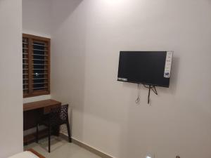 Elle comprend une télévision à écran plat suspendue au mur. dans l'établissement SRI BALAJI LODGING, à Tiruchchendūr