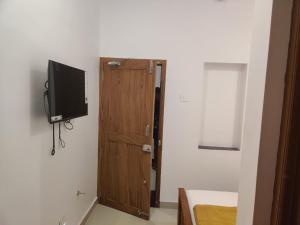 Cette chambre dispose d'une porte et d'une télévision murale. dans l'établissement SRI BALAJI LODGING, à Tiruchchendūr