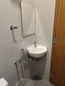 La salle de bains est pourvue d'un lavabo et d'un miroir. dans l'établissement SRI BALAJI LODGING, à Tiruchchendūr