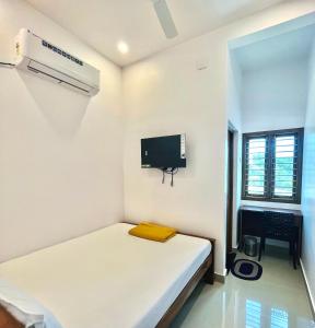 a small white room with a bed and a tv at SRI BALAJI LODGING in Thiruchendur