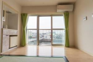 an empty room with a large window with green curtains at 紀州鉄道片瀬江ノ島ホテル in Fujisawa