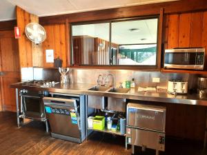 a kitchen with a sink and a microwave at Wild Nature Lodge, Mareeba Wetlands in Biboohra