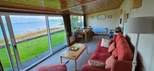 a living room with a red couch and a view of the ocean at The Old Ferryhouse in Port Appin